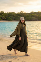 Model trägt die beige MIKA Cap über dem Swim-Hijab – am Strand im Golden-Hour-Licht